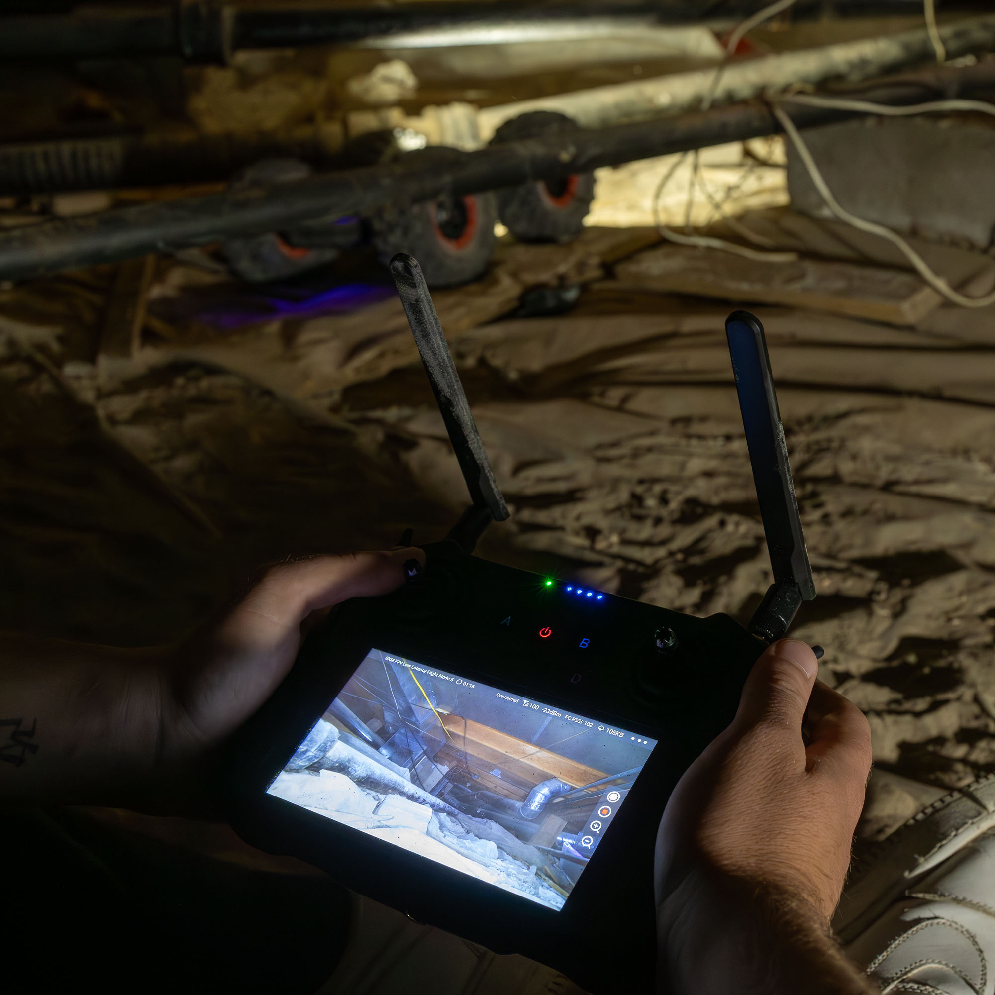 Handheld controller displaying live video from a crawlspace inspection robot